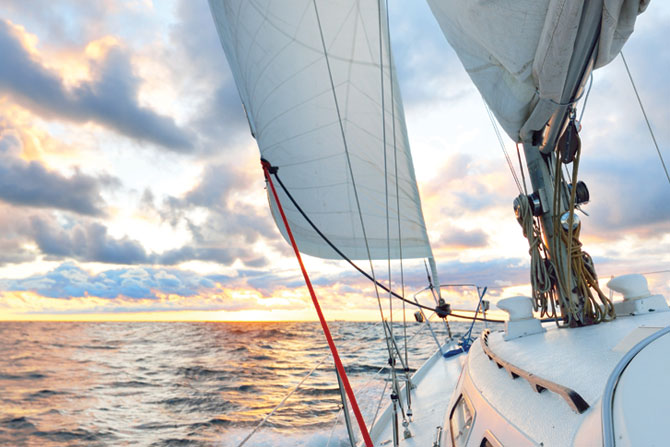 Yacht sailing in an open sea at sunset. Close-up view of the dec